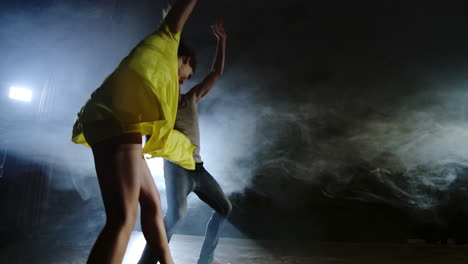 Zoom-camera-a-female-dancer-jumps-onto-her-partner-shoulder.-Acrobatic-dance-musical-on-stage-in-smoke.-Contemporary